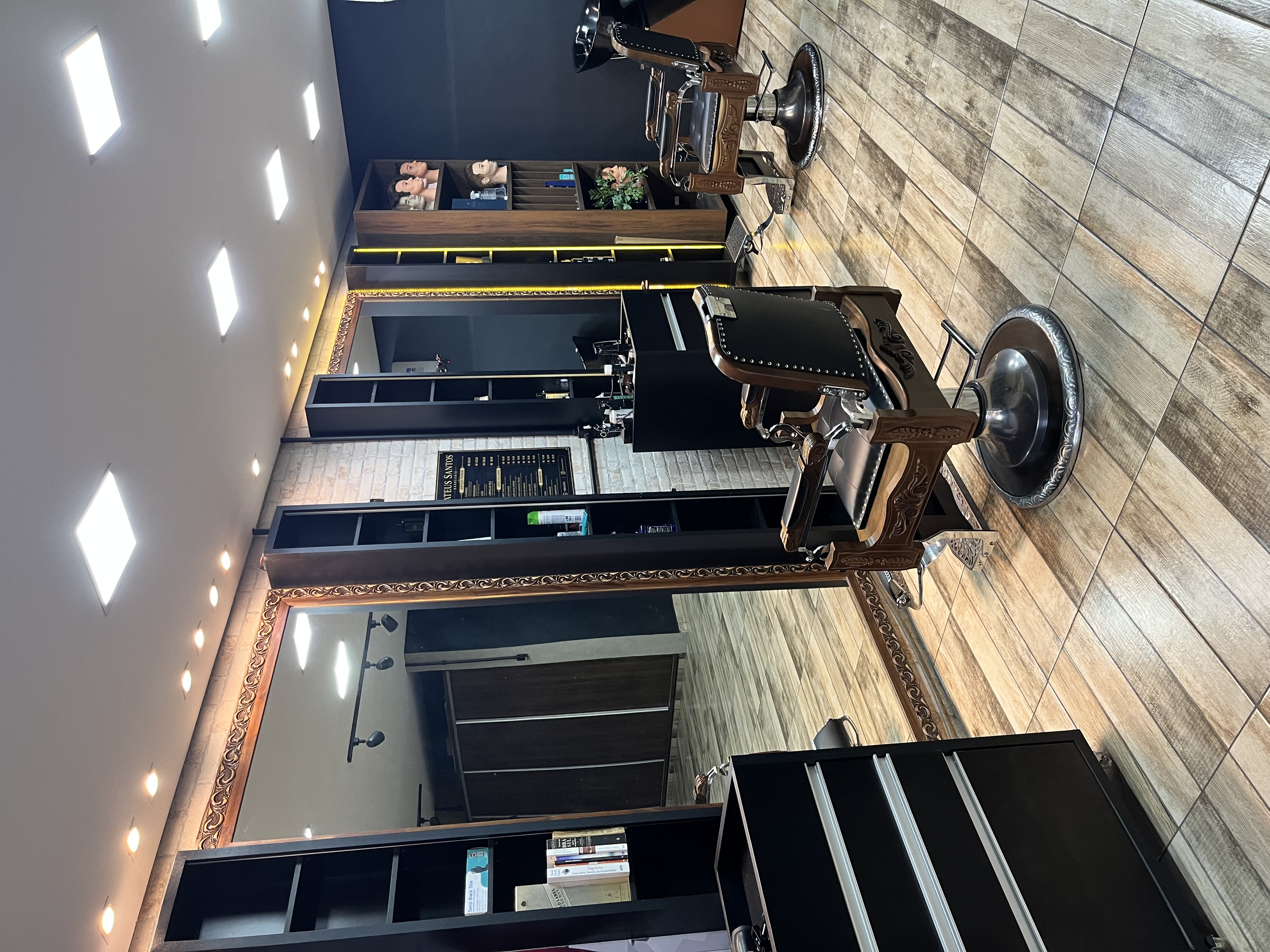 Interior da barbearia Mateus Santos, cadeiras clássicas e espelho emoldurado em dourado